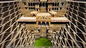 A monumental stepwell with cascading symmetrical stairs descending to emerald water